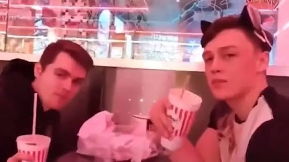 Two friends at a diner with milkshakes; one wears playful cat ears