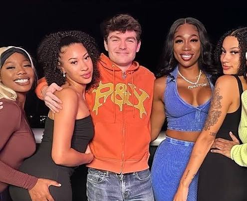 Nick Fuentes posing with a group of women at an outdoor evening gathering